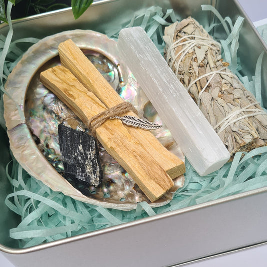 Energy cleansing kit with sage, tourmaline, selenite, palo santo, and abalone shell neatly arranged in a reusable tin box.